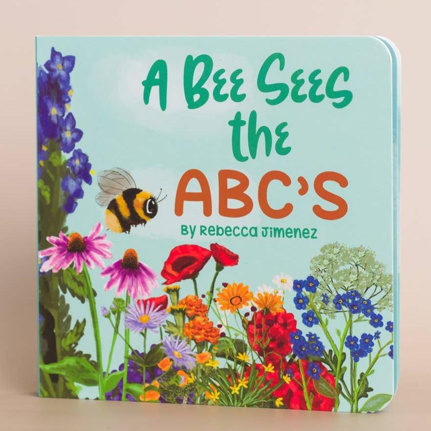 Honey - A Bee Sees The ABC's Baby Board Book straight-on view of front cover and illustration of bees and flowers. Book by Rebecca Jimenez.