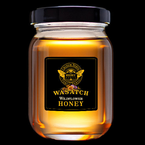 Honey - Wasatch Local Wildflower Honey = Pure, Raw, Unfiltered Wildflower Honey in a glass jar and black metal lid,  backlit and glowing golden amber colors by Higbee Honey on a black Background.