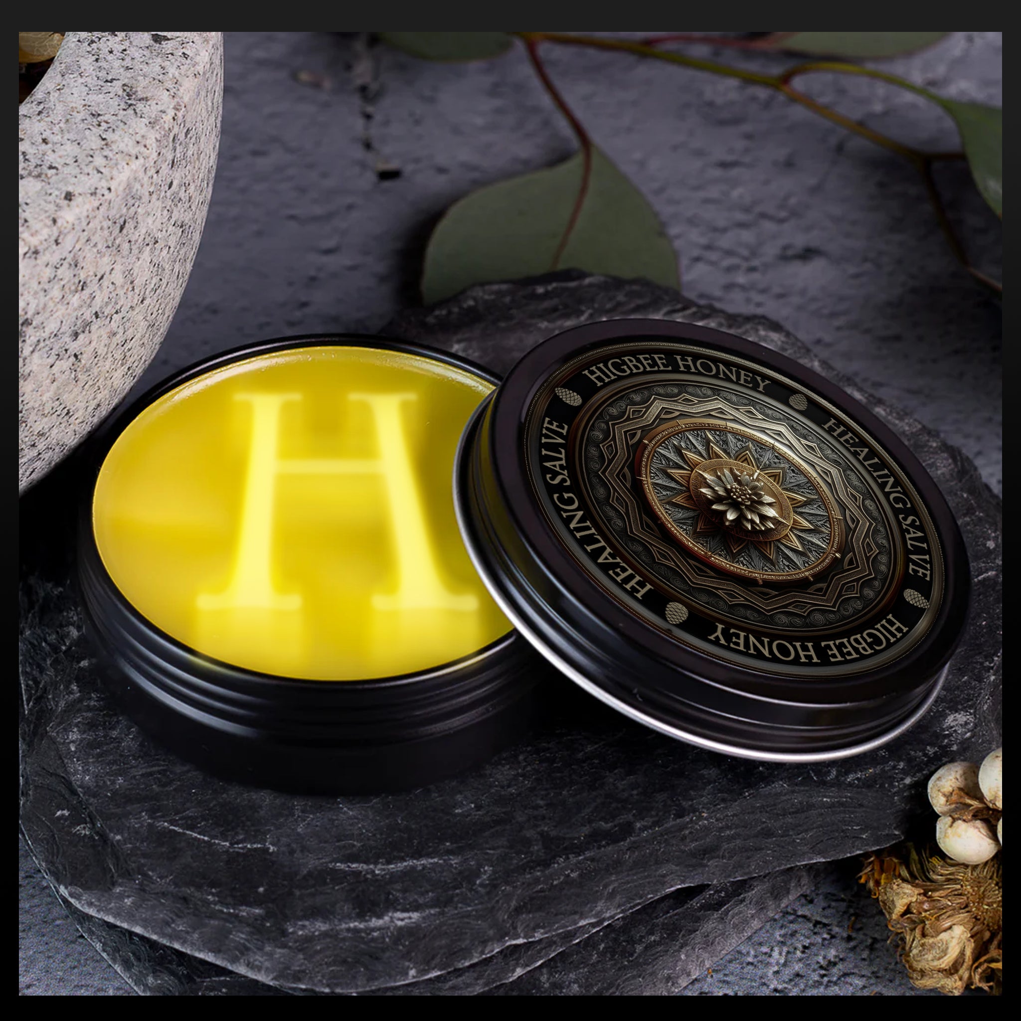 Gift Packages & Sets - Higbee Honey Healing Salve tin sitting on a dark gray stone with it's lid askew revealing a gorgeous golden salve inside. There are a few leaves and the side of a mortar and Pestle hitting mostly out of the image on the left. The beautiful lid label is showcased.