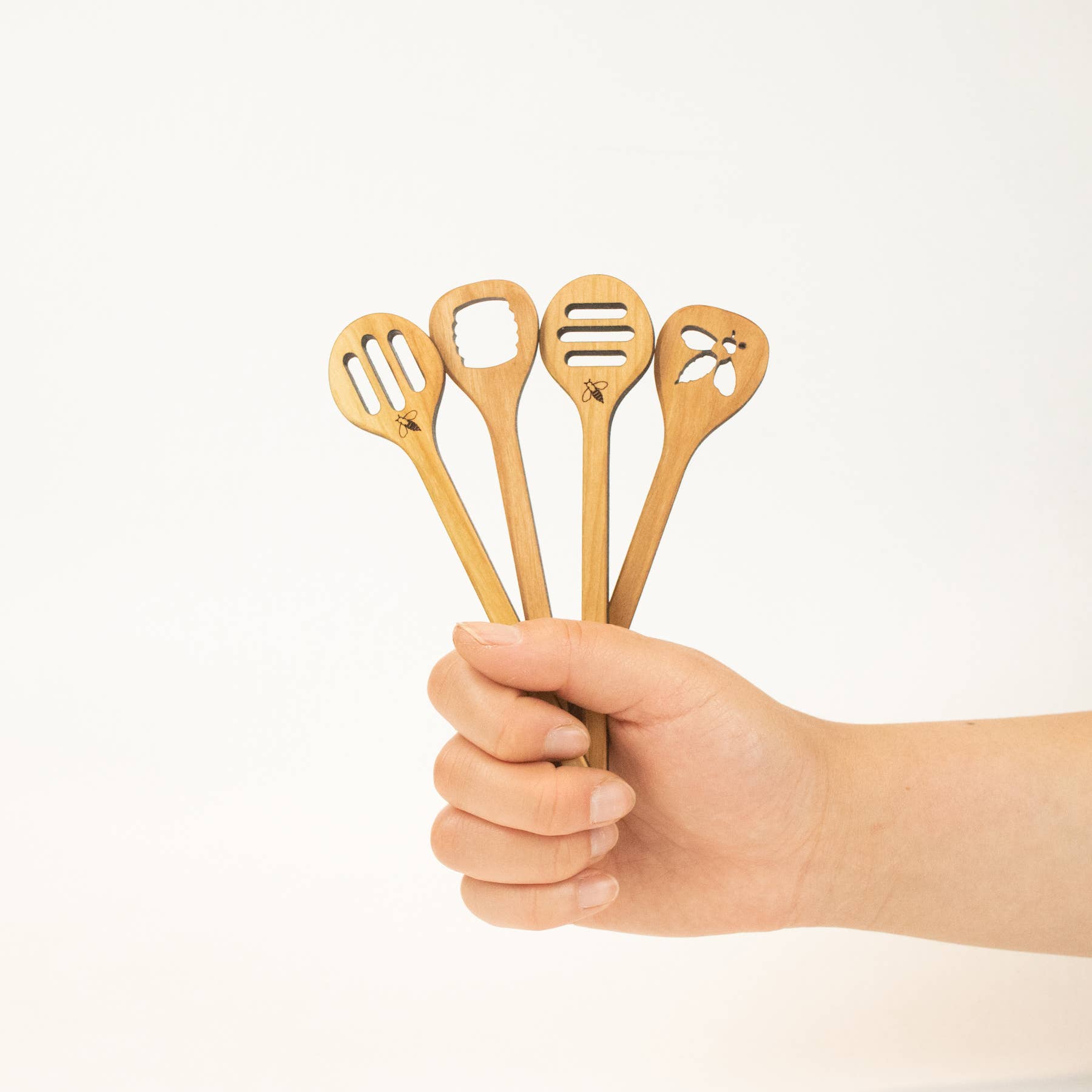 Higbee Honey laser Cut Honey dipperall four types held by a hand  on a white background
